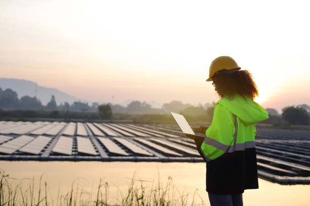 journée internationale de la femme, une travailleuse utilisant un ordinateur portable sur le site de la ferme solaire flottante - solar panel engineer solar power station women photos et images de collection