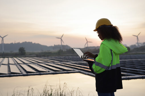International Women's Day, Female worker using  laptop work on the site of the floating solar farm and windmill