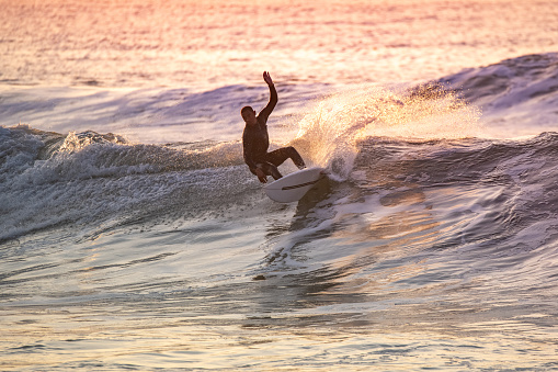 Sporty boy riding his surf board on the ocean wave.