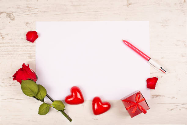 a red rose, two decorative hearts and a gift box lie on a table with a white sheet of paper and pen. mockup for writing text congratulations on valentine's day or declaration of love, or wedding, - wedding reception valentines day gift heart shape стоковые фото и изображения