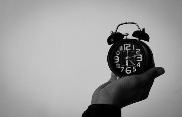 Man's hand holding a black alarm clock. time to wake up