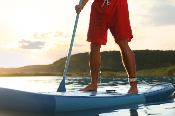 istock Man paddle boarding on SUP board in river at sunset, closeup 1918155276