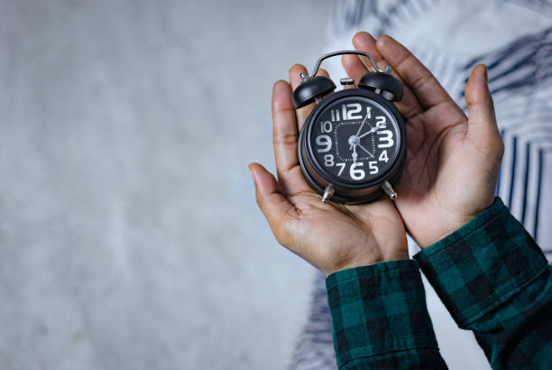 istock Man's hand holding a black alarm clock. time to wake up 1918155334