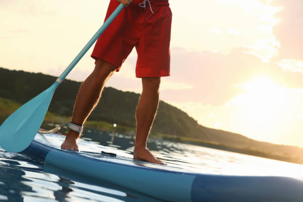 istock Man paddle boarding on SUP board in river at sunset, closeup 1918155783
