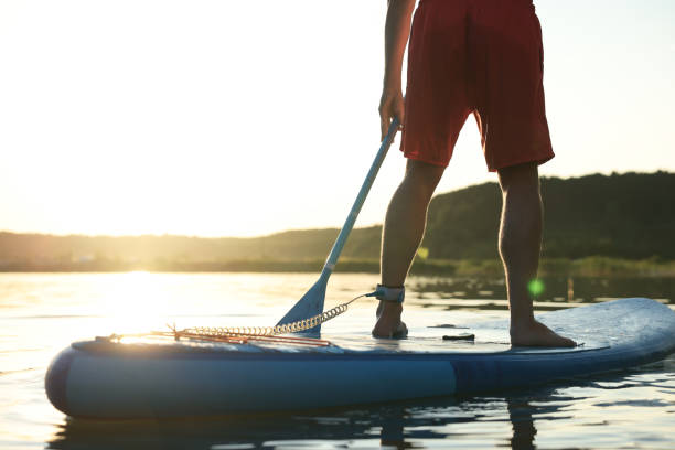 istock Man paddle boarding on SUP board in river at sunset, closeup 1918158763