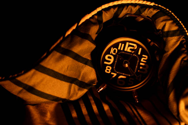 Black alarm clock on the bed. Time to sleep