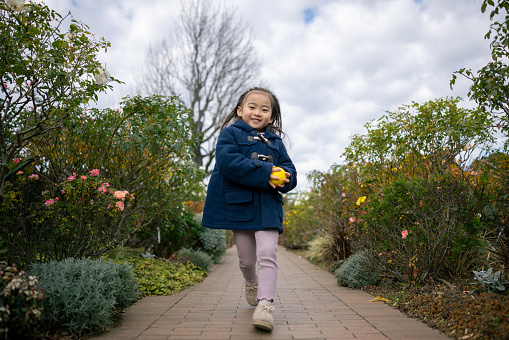 Little girl running in flower garden - low angle view