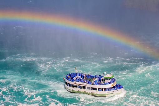 Niagara, Ontario, Canada. Jun 7, 2023. Tourists on a boat tour at Niagara Falls in the summer, with a rainbow emerging from the water mist.
