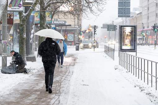 Stockholm, Sweden, Dec 22, 2023 A man walks with an umbrella in the rain at Medborgarplatsen on Sodermalm.