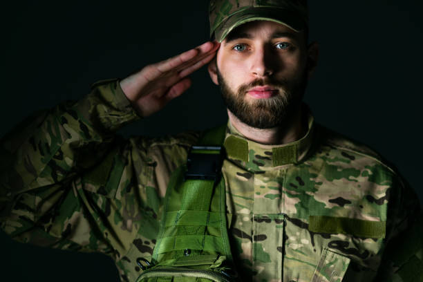 istock young marine corps soldier making a greeting gesture, against a dark background. 1918279259