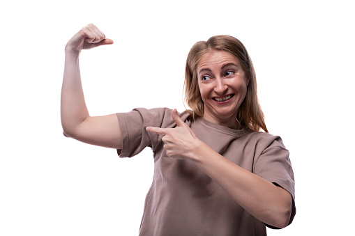 Portrait of a Caucasian blonde woman in a T-shirt showing her muscles.