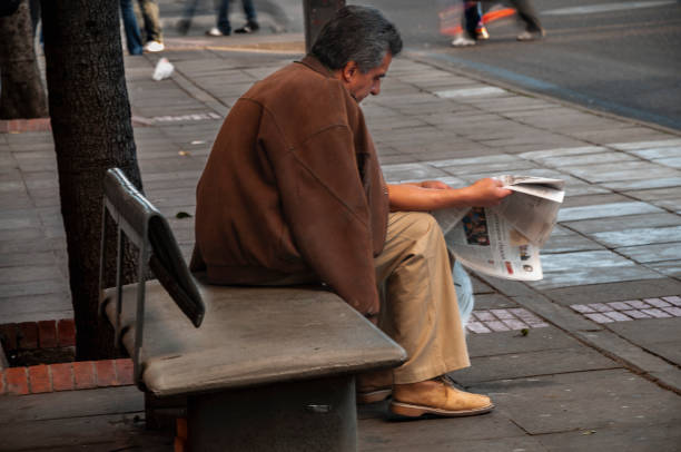 adult man sitting reading a newspaper on a street - news of the world imagens e fotografias de stock