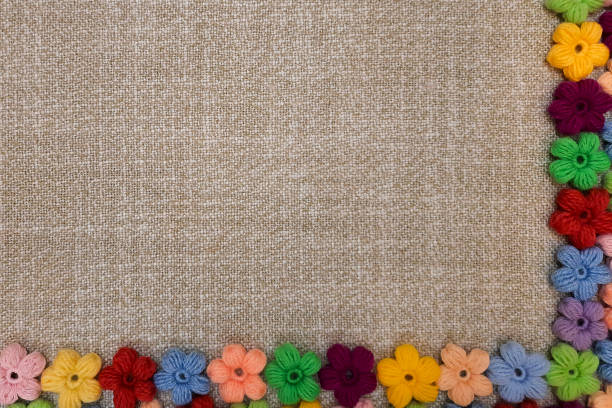 Flowers made of thread on rough natural fabric. Template background with copyspace. Concept of needlework, craft, folk traditions. Top view. Space for text.