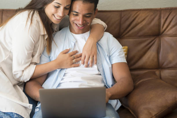 istock Young couple moving to a new home relaxing sitting on the sofa using computer laptop, smiling happy for moving to new apartment 1918357632