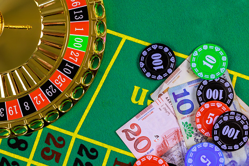 Casino roulette is on green gaming table with Georgian banknotes lari, poker chips.