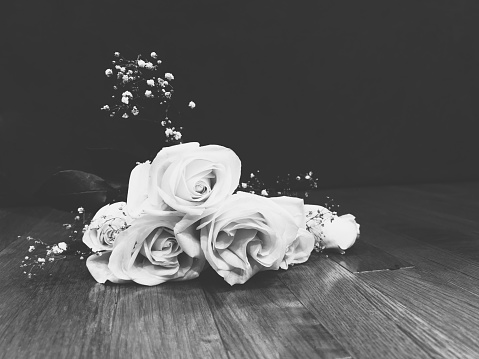 Black and white rose bouquet on hardwood floor.