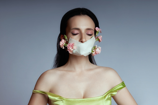 Woman with mask on face from which flowers grow, beauty portrait spring allergy, respiratory protection