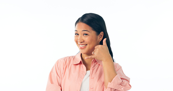 Portrait, woman and smile for call me, hand sign and communication in studio on white background. Happy asian model, talk and emoji gesture for telephone chat, conversation and contact for networking