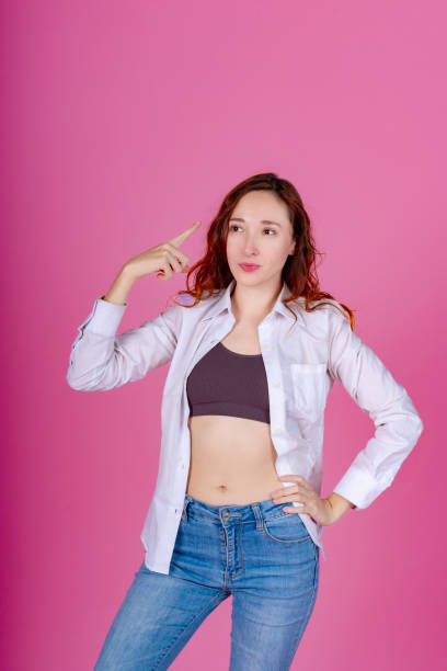 istock Thoughtful Redhead Woman Pointing to Head on Pink 1918393689