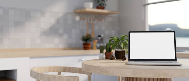 istock A white-screen laptop mockup on a minimal wooden dining table in a modern bright and clean kitchen. 1918521038