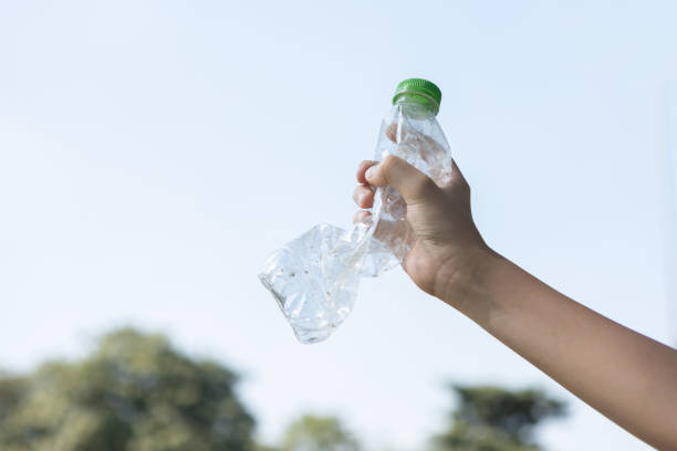 istock Recyclable can waste held in hand up on sky isolated background. Gyre 1918525925