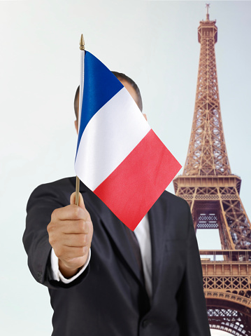 Businessman holding a French flag in front of Eiffel Tower in Paris