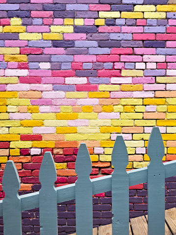 Full frame photo of a fence in front of a colorfully painted brick wall texture from a building