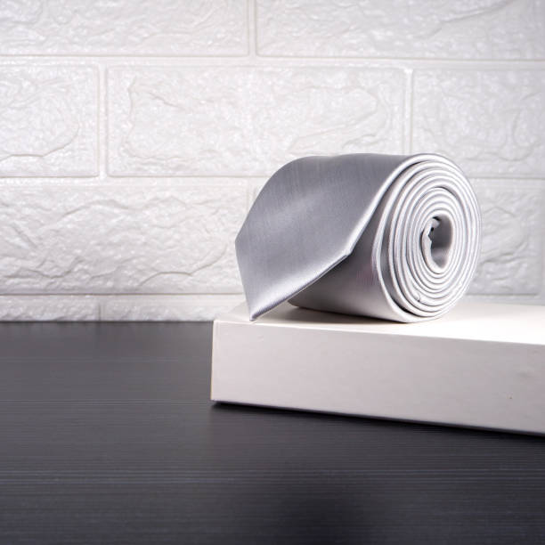 istock Plain fabric white necktie rolled on gift box with white wall background close-up view single object 1918698822