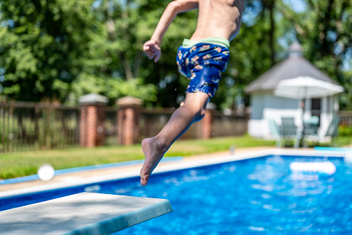 Selective focus on a swimming board as a young boy jumps into a pool. . High quality photo