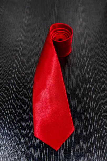 Unrecognizable adult man wearing a black suit and adjusting his red necktie