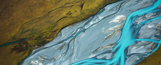 The beauty of New Zealand's South Island with this stunning aerial photograph capturing the serpentine flow of a river against the backdrop of the iconic Mount Cook. From high above, the intricate patterns of the water winding through the landscape create a mesmerizing scene. The rugged terrain, snow-capped peaks, and pristine river combine to showcase the untamed splendor of nature. Ideal for conveying a sense of adventure, exploration, and the grandeur of New Zealand's wilderness.