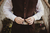Man buttoning up tweed vest