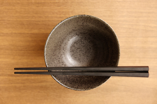 Empty bowl and chopsticks on a wooden background. Top view.
