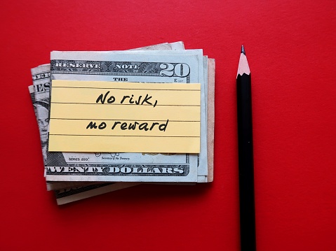 Pencil and cash dollar money on red background with handwritten note NO RISK NO REWARD - means willing to take a risk on things in order to gain whatever we desire in life, business or investment