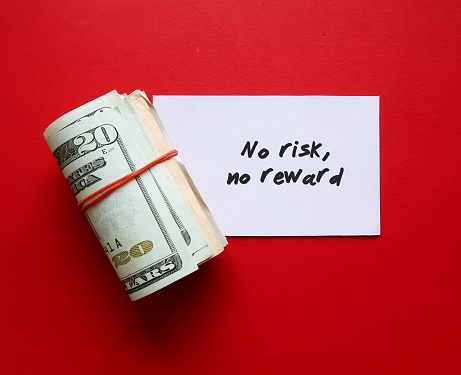 Cash dollar money on red background with handwritten note NO RISK NO REWARD - means willing to take a risk on things in order to gain whatever we desire in life, business or investment