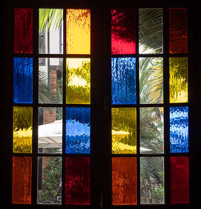 Colorful stained glass filters sunlight as it falls upon the chapel window sill.