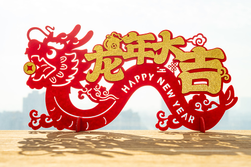 Chinese New Year of Dragon mascot paper cut in front of window English translation of the Chinese words are good luck in the year of dragon and no logo no trademark