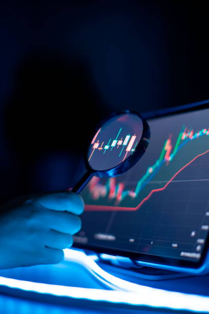 istock Businessman analyzes investment charts using a magnifying glass. 1918926451