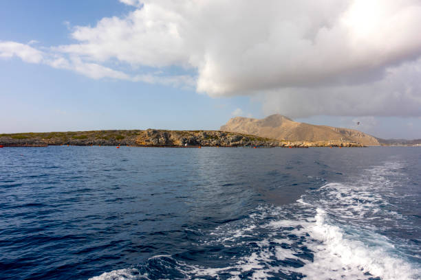 Ancient limestone area on Favignana Island, Sicily, with rugged rock formations, sparse vegetation, and a deep blue sea under a bright sky in the background