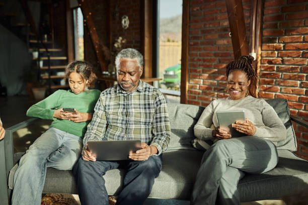istock Black grandparents and their granddaughter using wireless technology at home. 1918948490