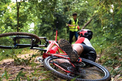 Mountain Bike Accident Cyclist Falls and Suffers Injury in Practice Activities Cycling Sports in Natural Park, Urgent Aid Required from First Aid Staff Assistant.