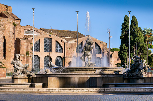 A scene with the Fontana delle Naiadi (Fountain of the Naiads) in the center of Piazza della Repubblica (Republic Square), in the historic heart of Rome, with the archeological remains of the Terme di Diocleziano (Baths of Diocletian) in the background. The Fountain of the Naiads was built in 1870 during the pontificate of Pope Pius IX, a few days before the conquest of Rome by the troops of the Kingdom of Italy and the end of the temporal power of the papacy, by the artists Mario Rutelli e Alessandro Guerrieri. Piazza della Repubblica is located on the edge of the Rione Monti and the central Via Nazionale. In 1980 the historic center of Rome was declared a World Heritage Site by Unesco. Image in high definition quality.