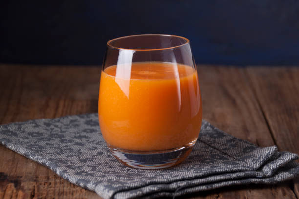 Pumpkin juice in a glass goblet on a wooden table stock photo