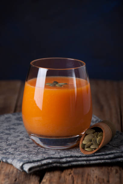 Pumpkin juice in a glass goblet on a wooden table stock photo