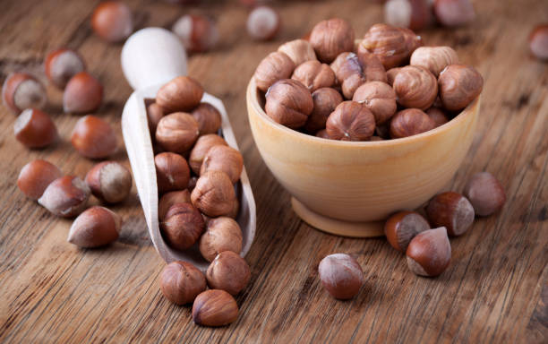 Hazelnuts in a  wooden spoon and wooden bowl stock photo