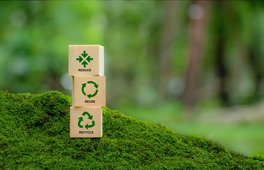 Words reduce reuse recycle on a wooden cube on green background. Ecology, sustainability, conscious consumerism, renew, concept.\nWaste management and a sustainable and economical lifestyle.