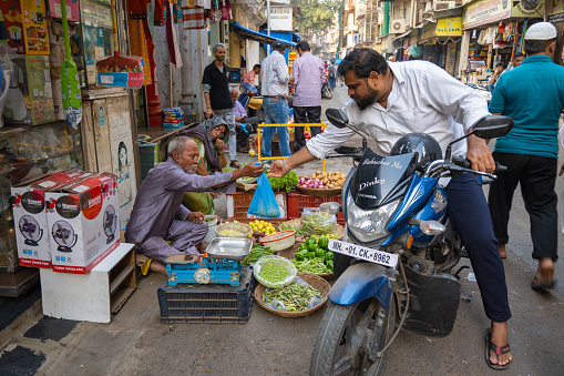 Mumbai, Maharashtra, India, 1st of January 2024, Indian man buying vegetables riding on bike,