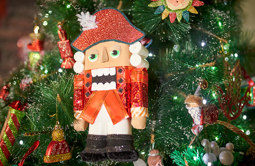 Christmas nutcracker toy soldier on Christmas background with fir tree branches, nuts, xmas balls. Christmas of New Year Greeting Card. Copy space. Toned retro image