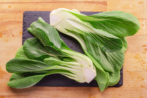 Fresh bok choy or chinese cabbage on slate stone cutting board. Top view.