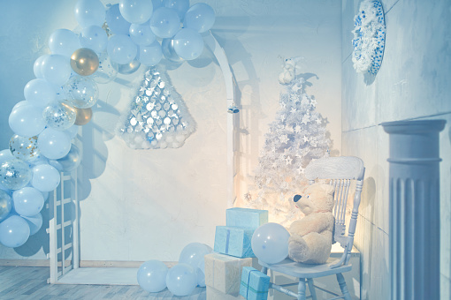 Christmas white and blue colors decor, wooden arch with balloons, white Christmas tree, studio shot